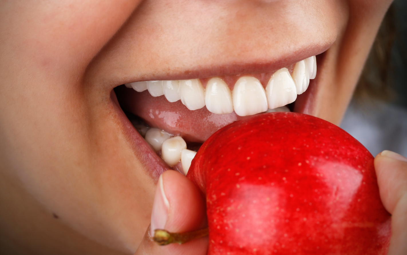 senhora a comer uma maçã com um sorrido branco 