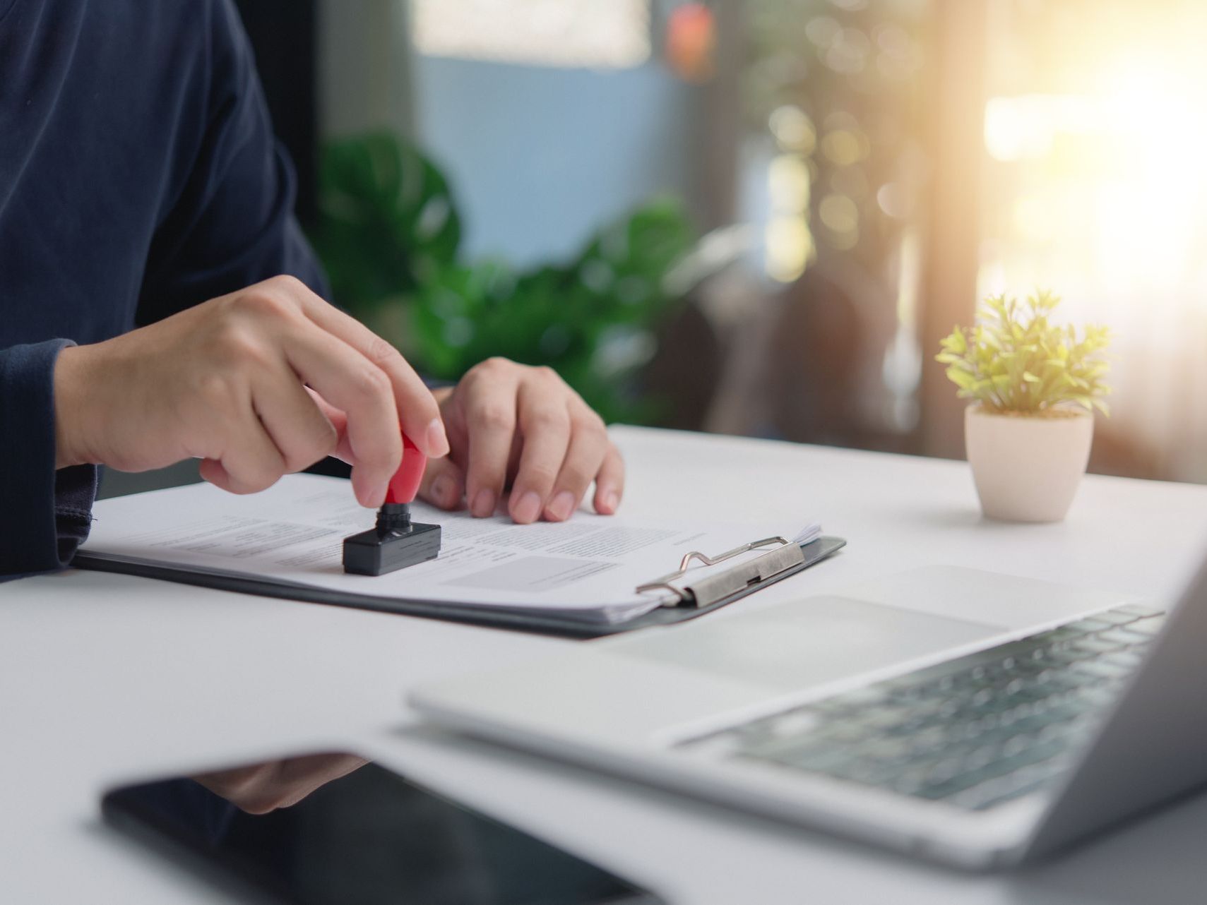 A person is stamping a document on a clipboard with a stamp.