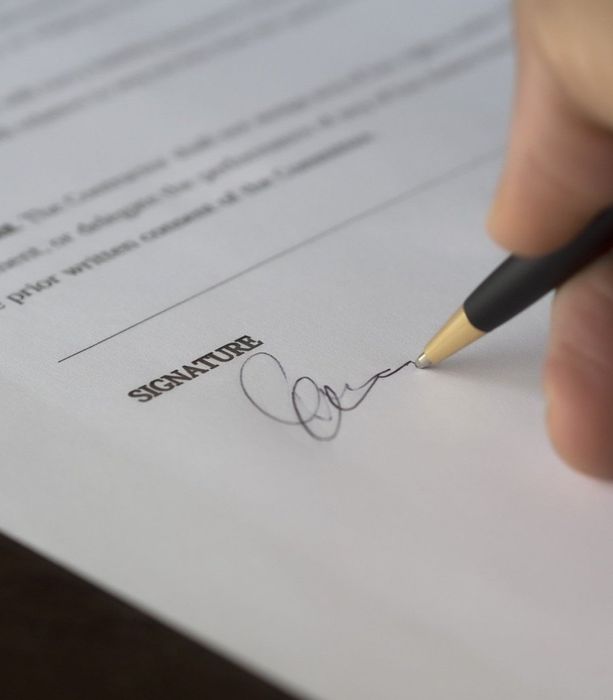 A person is signing a document with a pen.