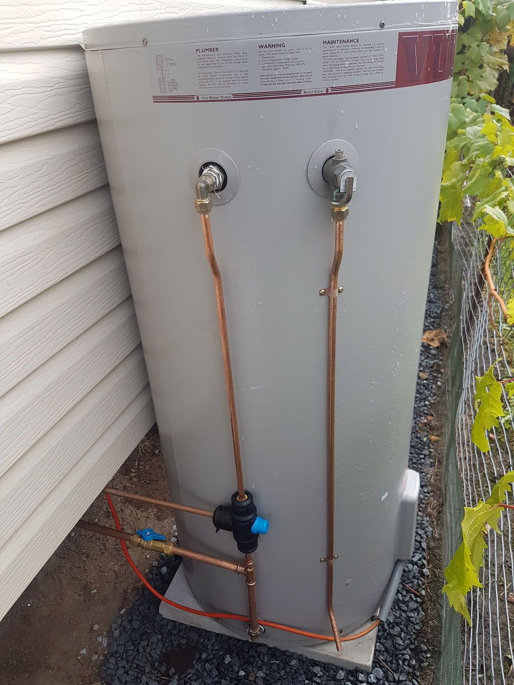 A Water Heater Is Attached to The Side of A House — Grant Wannan Plumbing in Wollongbar, NSW