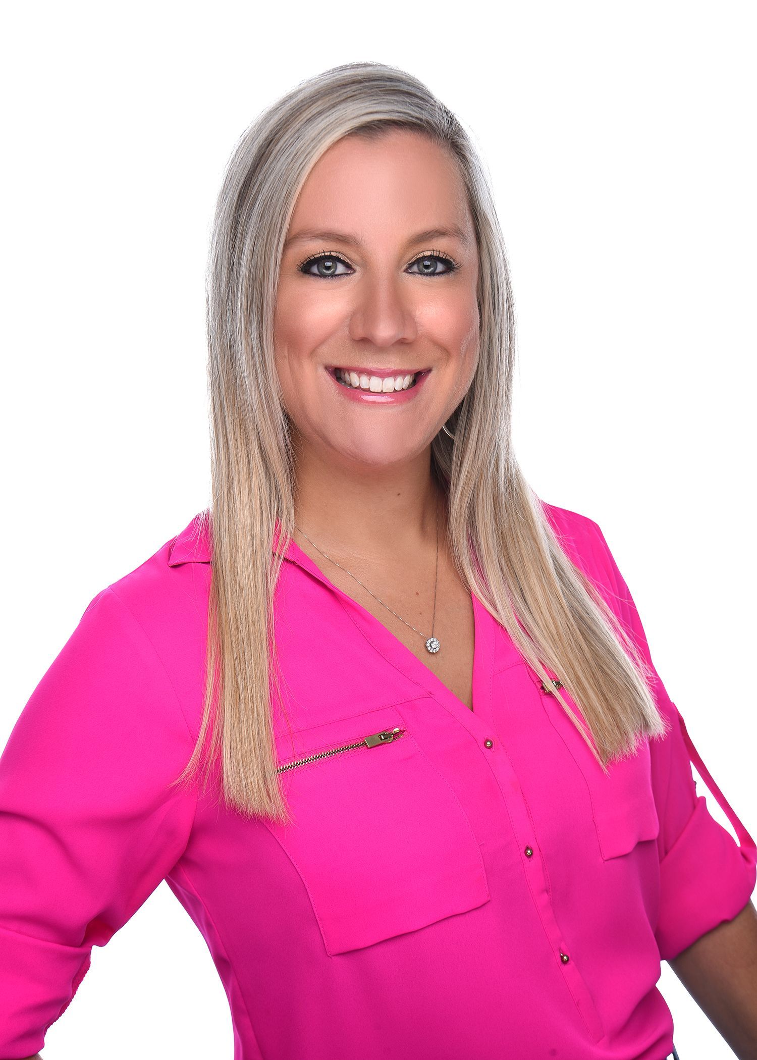 A woman in a blue shirt is smiling with her arms crossed