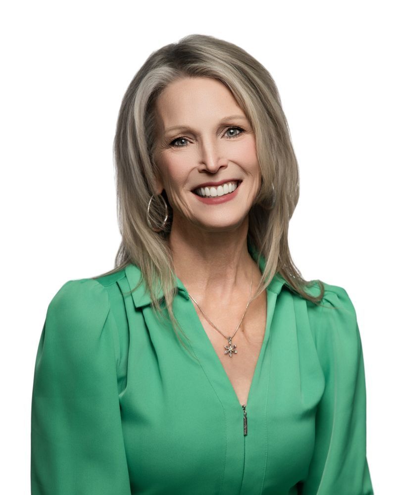 A woman is wearing a purple jacket and smiling for the camera.