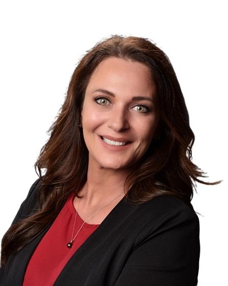 A woman wearing a red shirt and a black jacket is smiling for the camera.