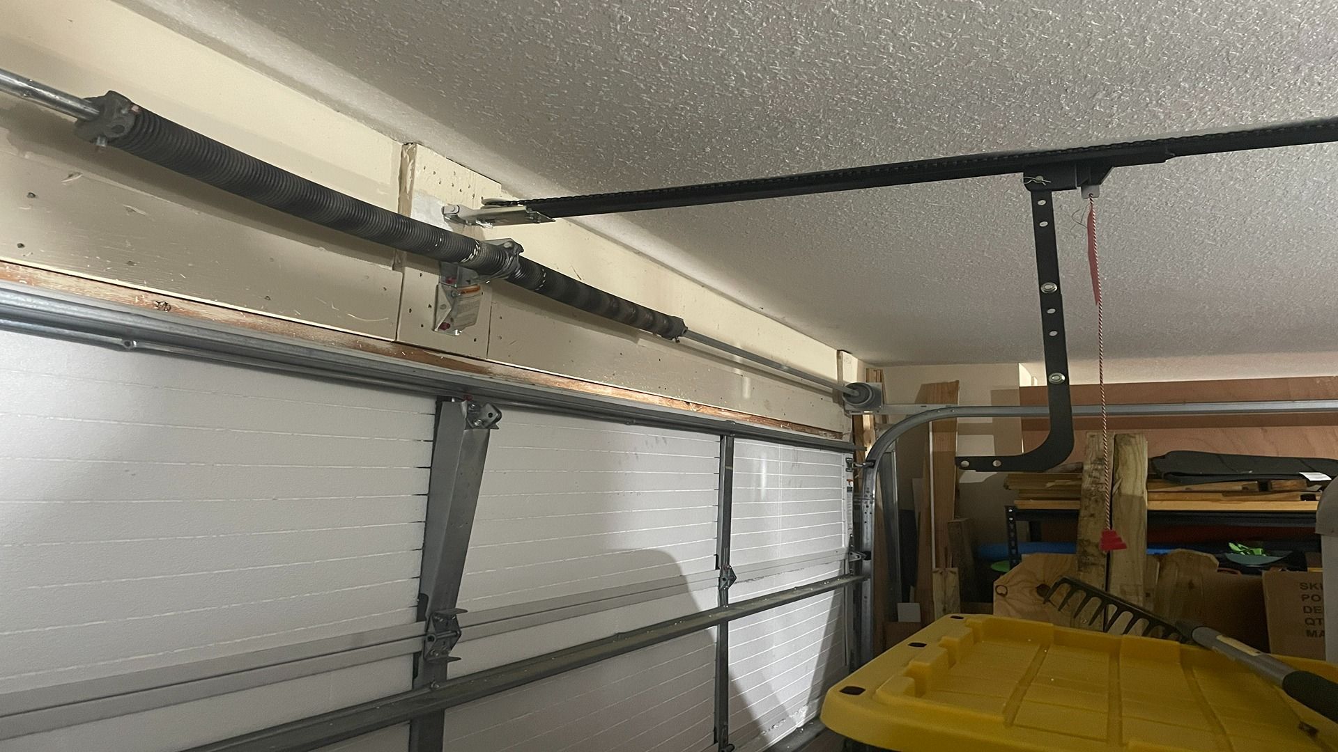 Close-up of a residential garage door torsion spring system mounted above the door panels inside a garage.