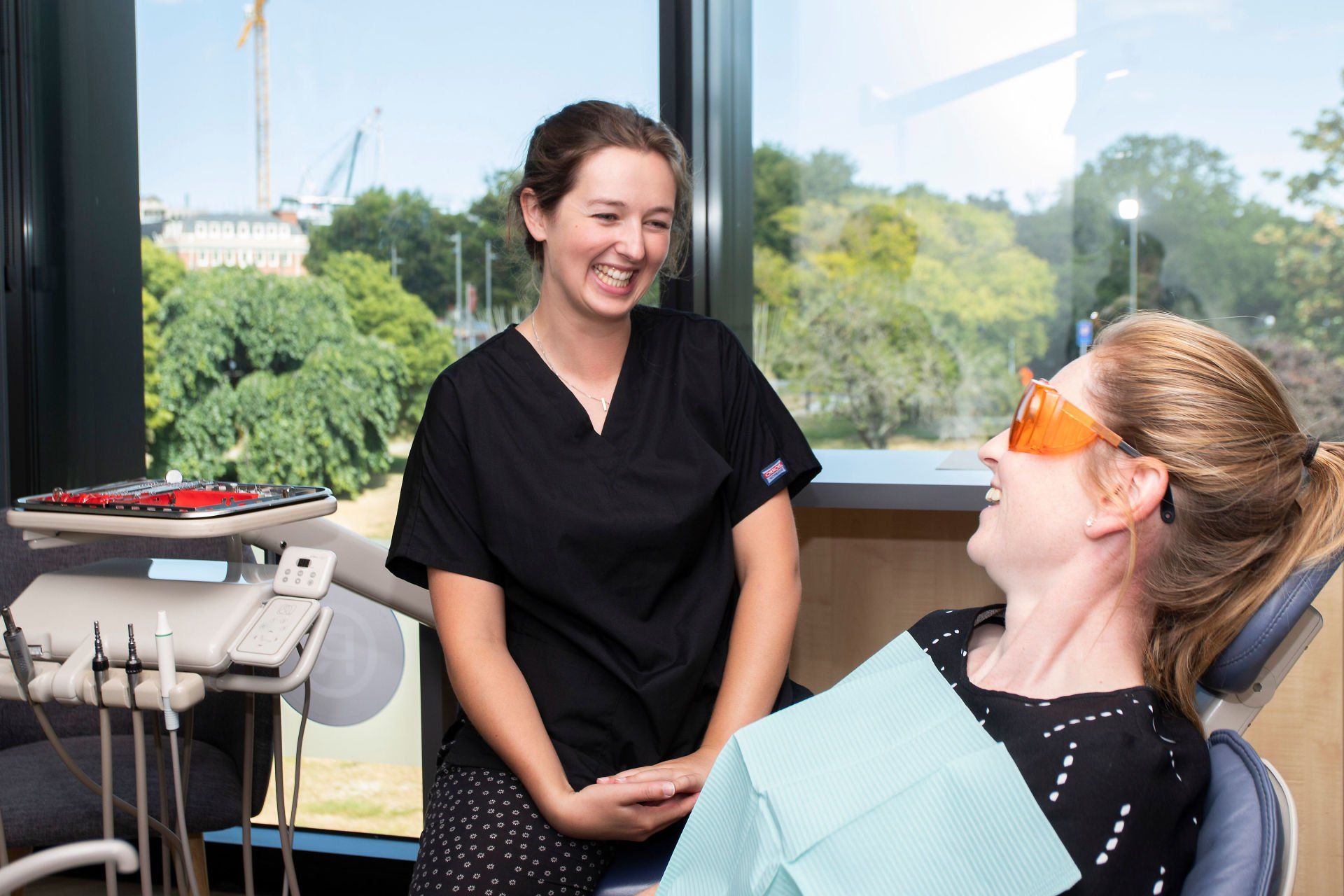 A woman is sitting in a dental chair talking to another woman