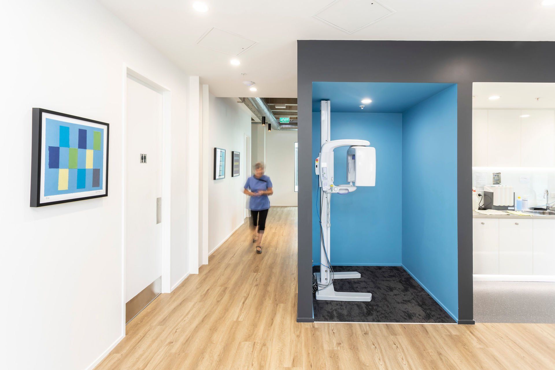 A person is walking down a hallway with a picture on the wall