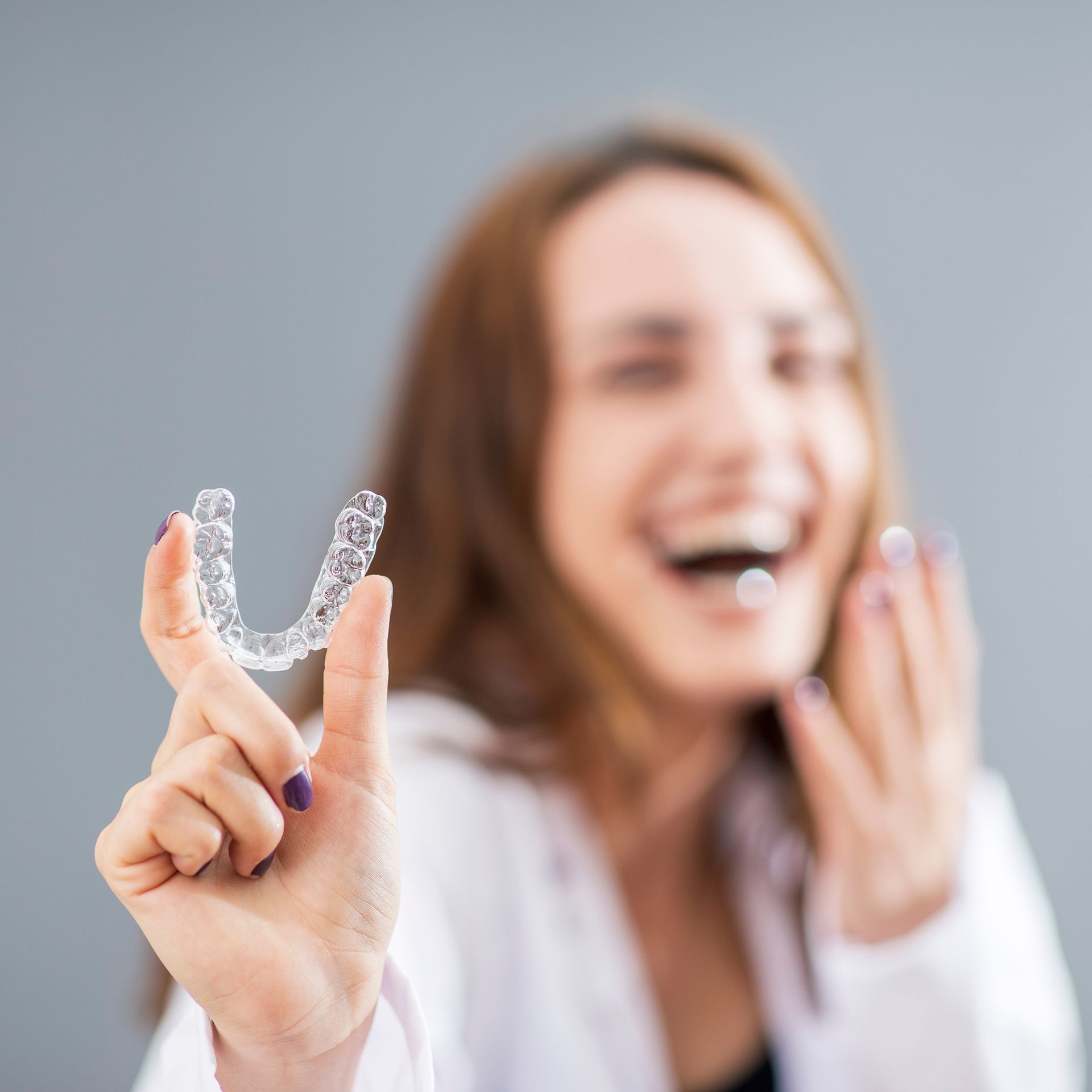 A woman is holding a clear mouth guard in her hand.