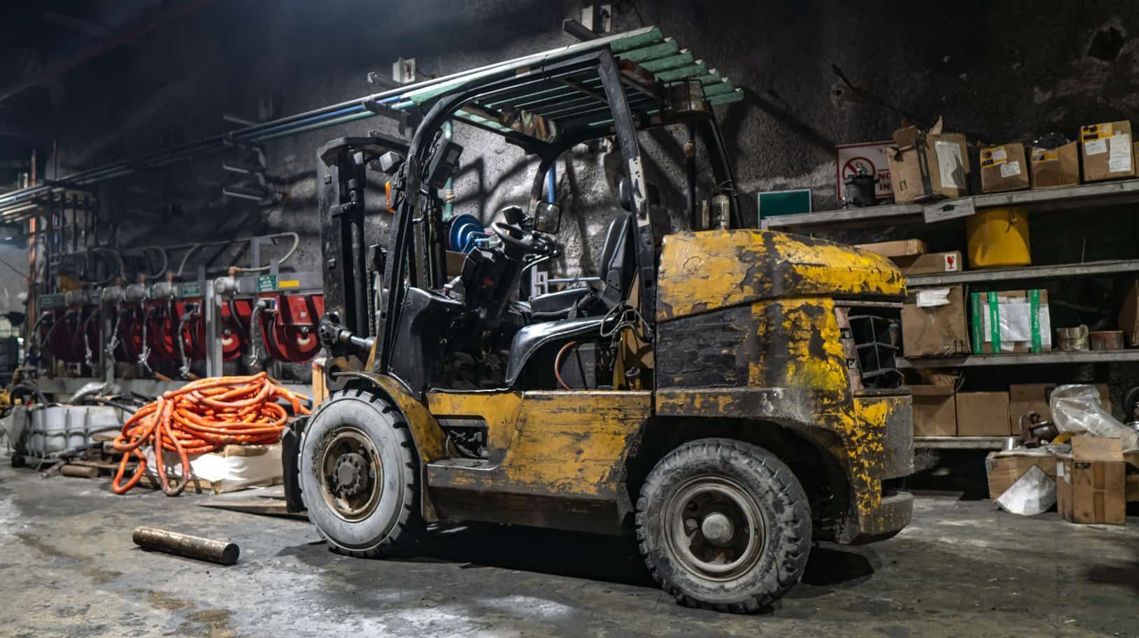 A Yellow Forklift is Parked in a Dark Garage — Secure Mine Solutions In Ryan, QLD