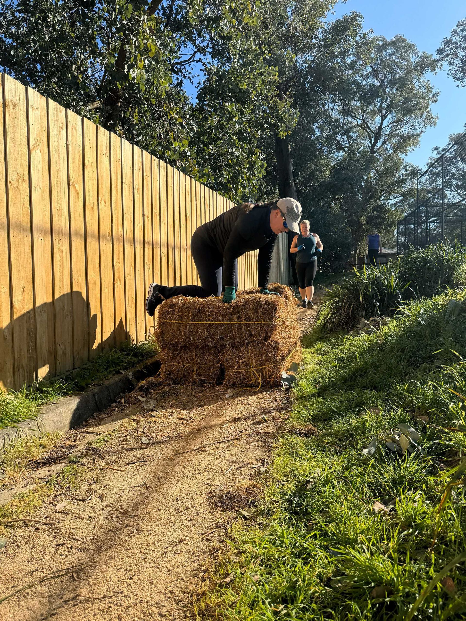 Members climbing over hay bales as part of obstacle course