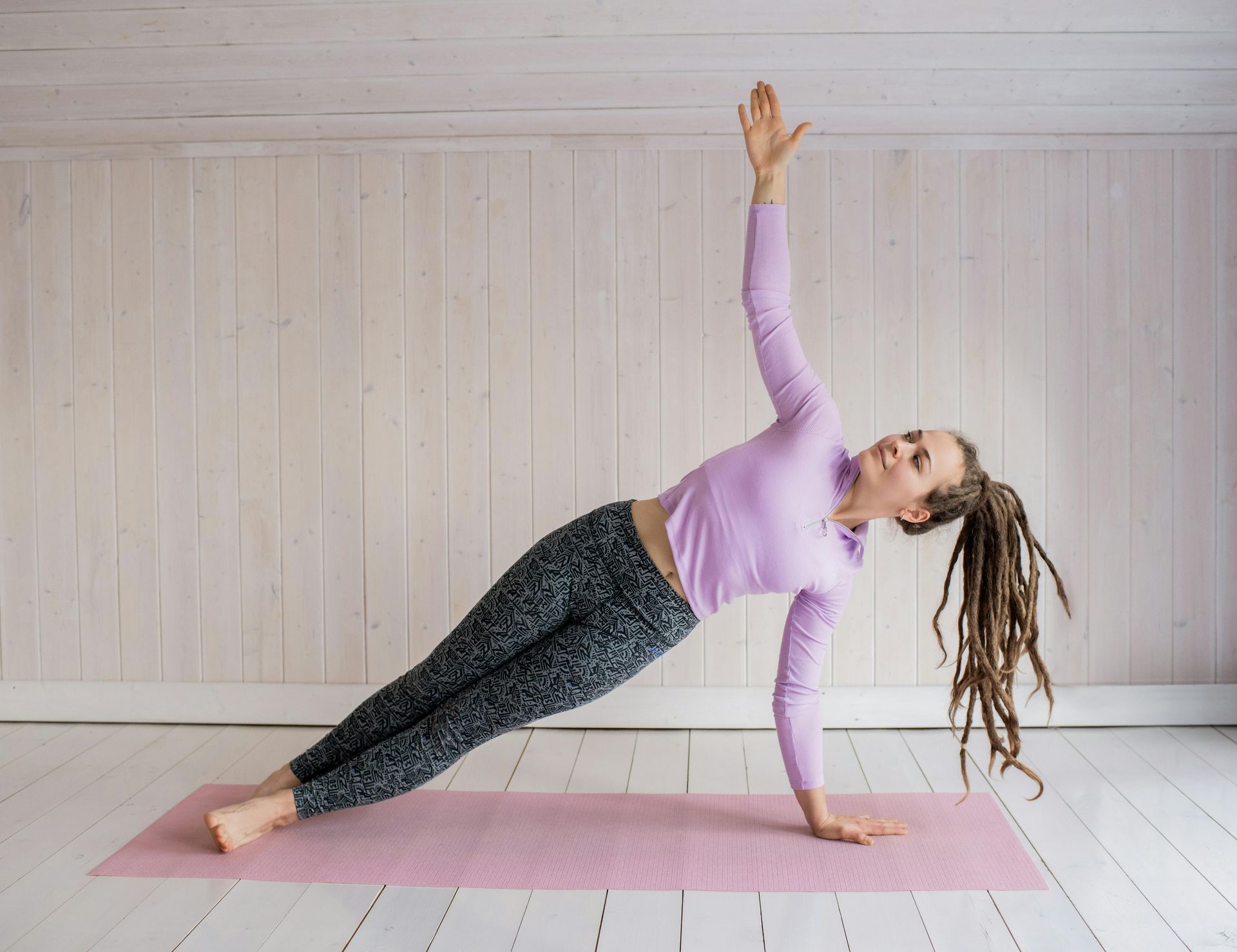 A woman with long hair in a side plank on a pilates mat
