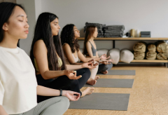 Two women on yoga mats stretching in a light-filled room
