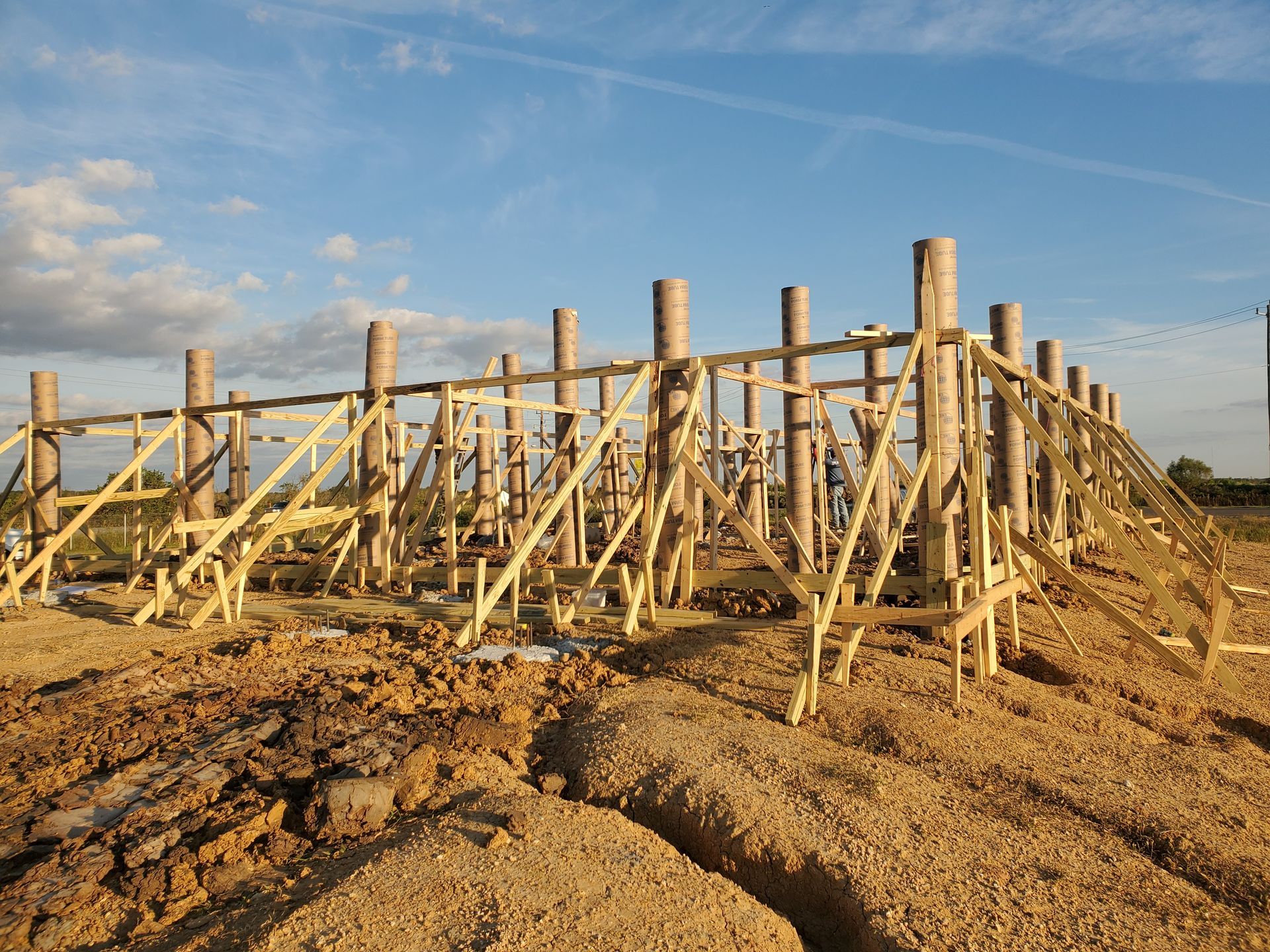Cylindrical digging tool covered in dirt, upright in soil. Construction site background.