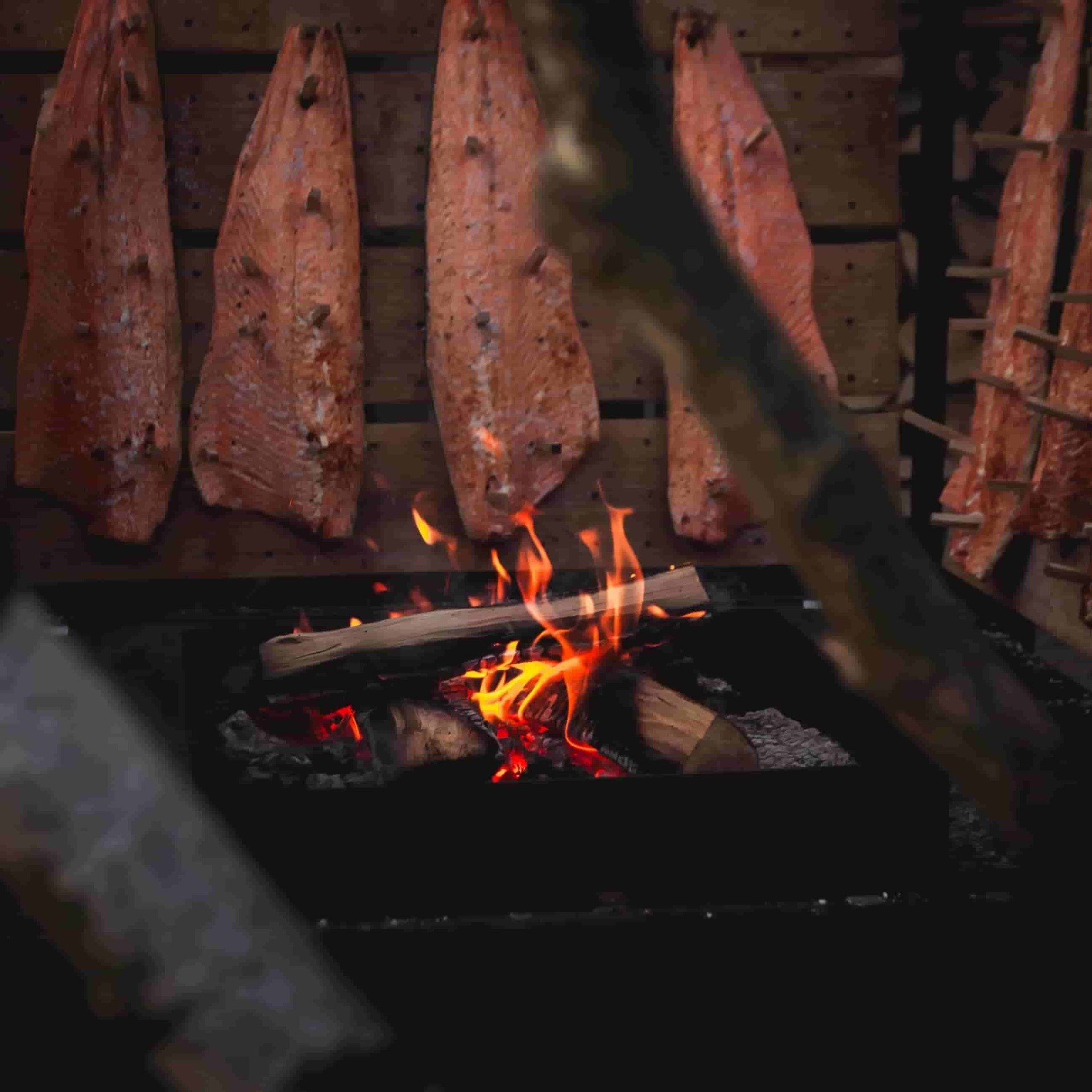 Smoked salmon on a string over fire in a smokehouse.