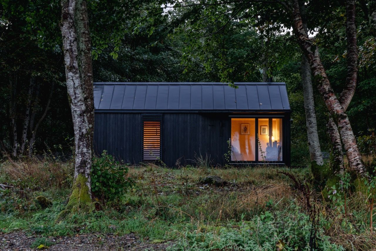 Exterior of modern black cabin at dawn.