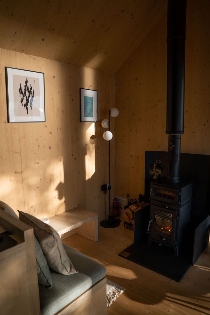 Light wood burning stove and minimalist artwork in a cabin.
