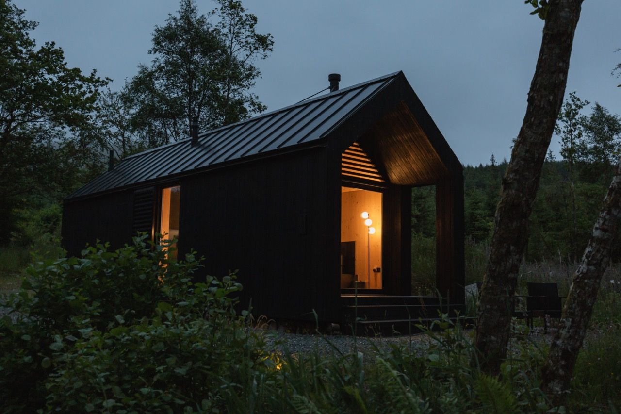 Exterior of modern cool black cabin at dusk.