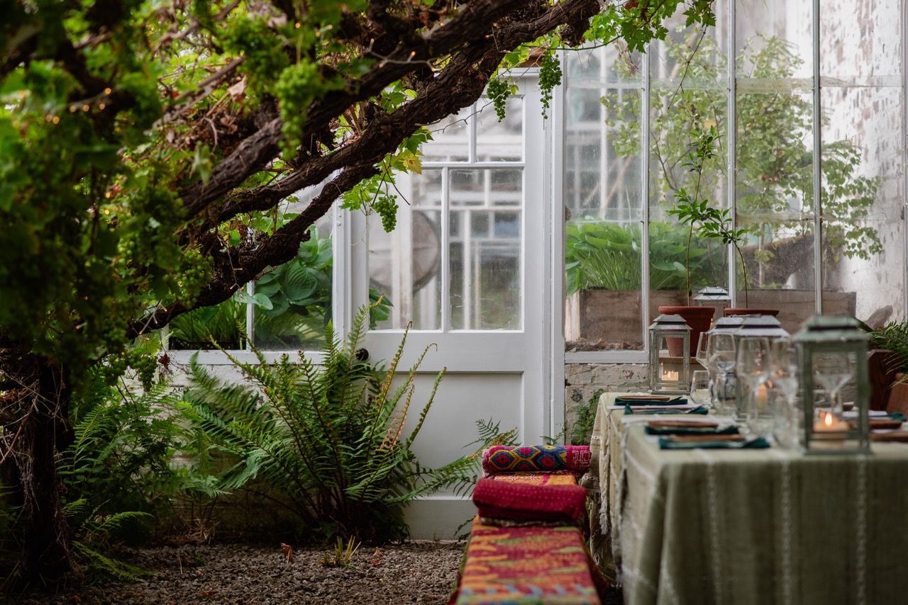 Table chairs and vines in a stunning greenhouse wild kabn kitchen