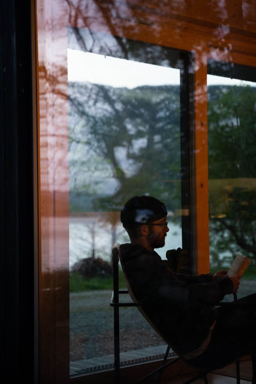 Man reading a book inside a cabin.