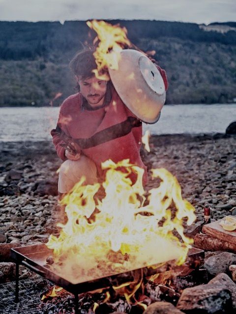 Chef william hamer cooking organic food over fire on the loch.