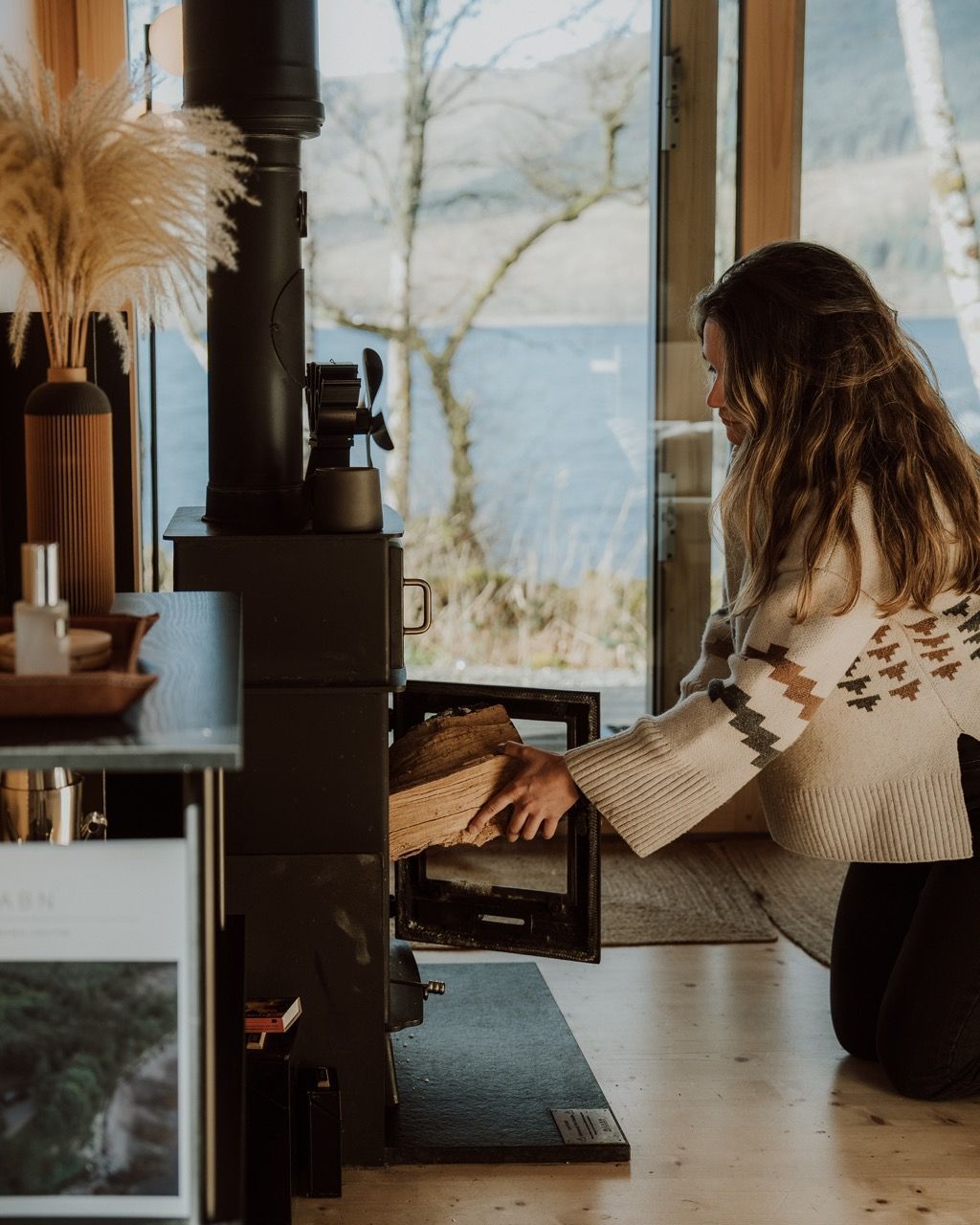 Modern luxury cabin interior wood burning stove next to sofa.