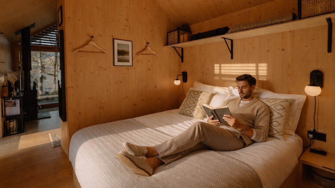 Guest relaxing on a king size bed inside a luxury off grid cabin in Scotland