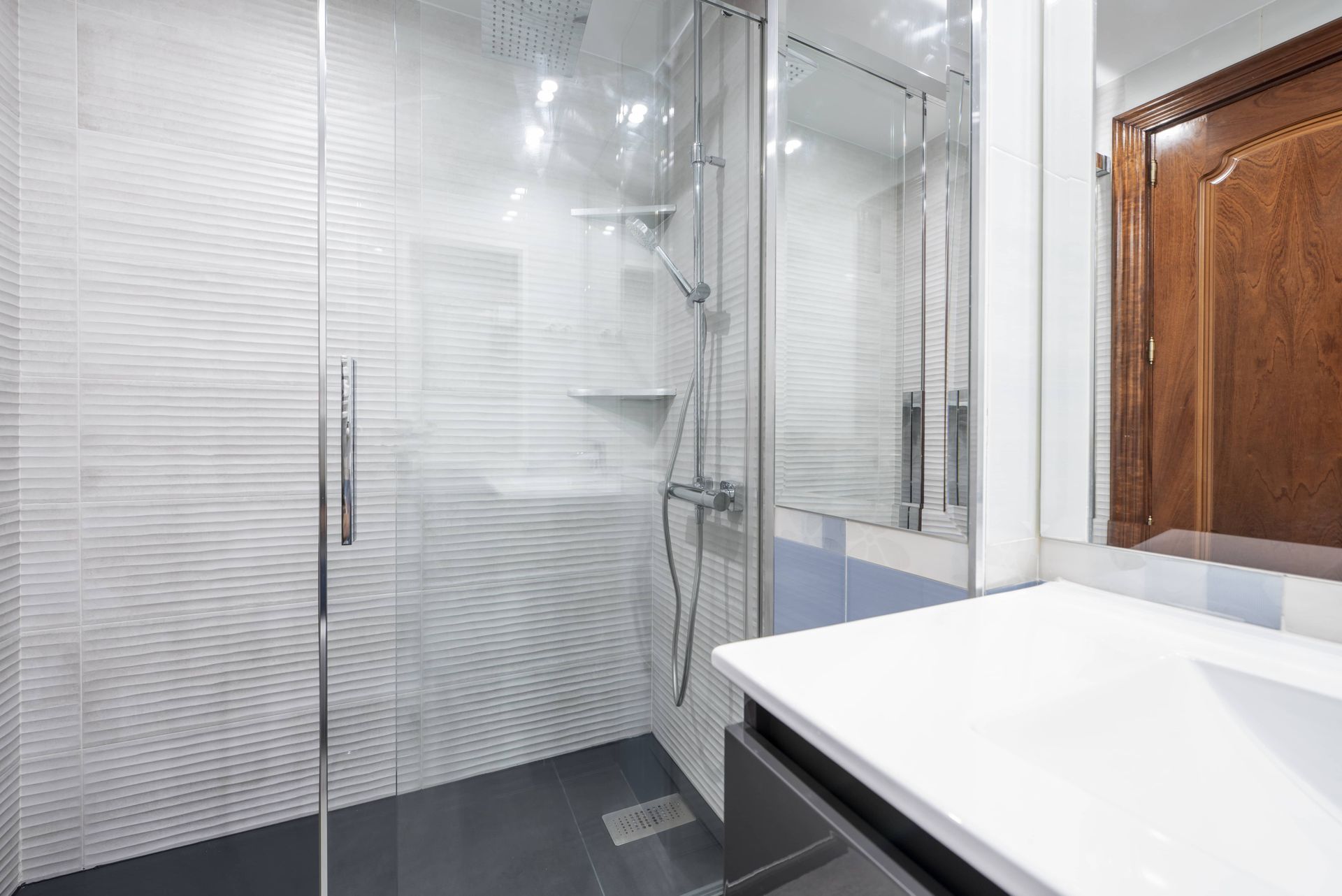 Modern bathroom with a glass shower, white countertop, and dark gray floor.