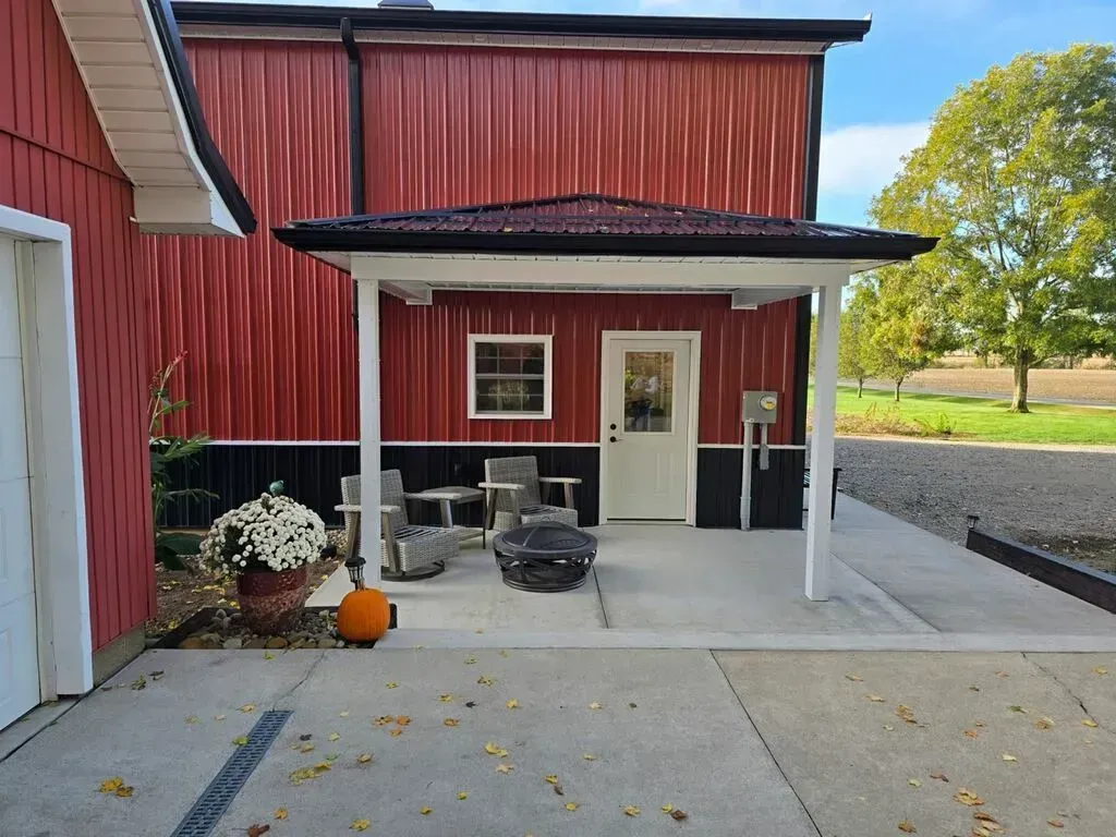 Red building with white-framed patio, chairs, and pumpkin.