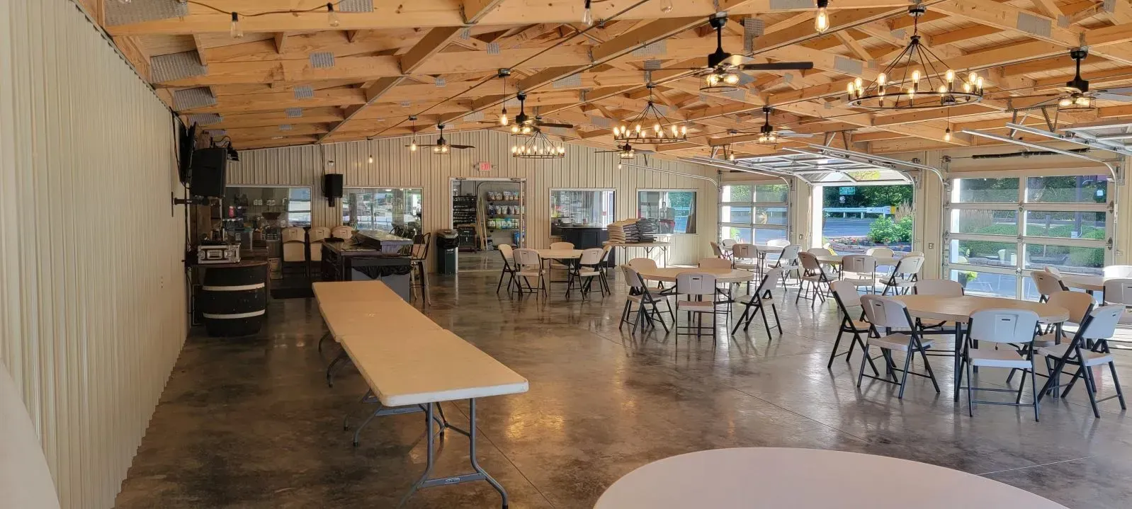 Event hall with tables, chairs, and string lights on a wooden ceiling.