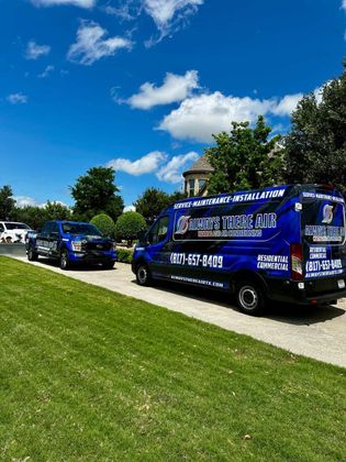 Blue service van and truck on a sunny street with a grass lawn. The van has business logos.