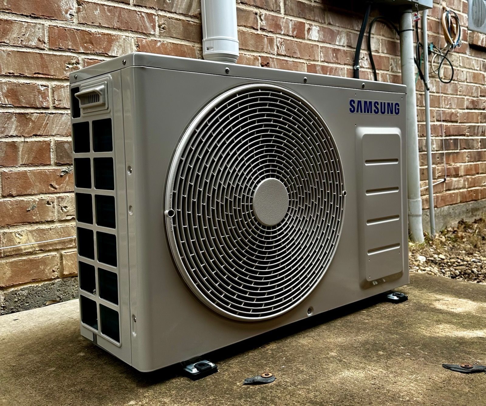Samsung outdoor air conditioner unit against a brick wall.