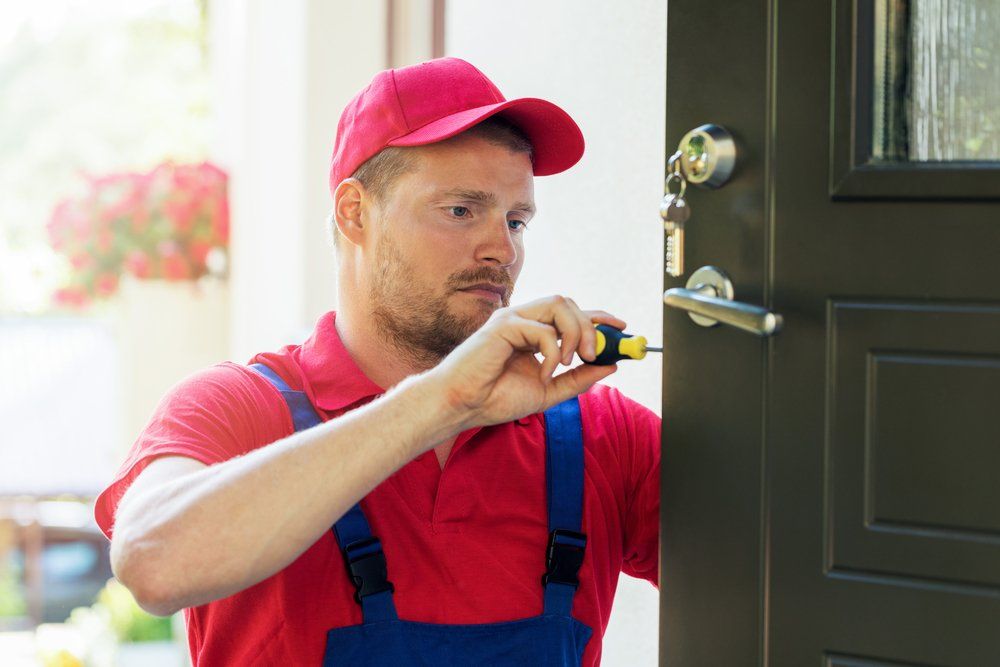 Locksmith in Red Uniform Installing New House Door Lock — CTS Locksmiths in Maroochydore, QLD