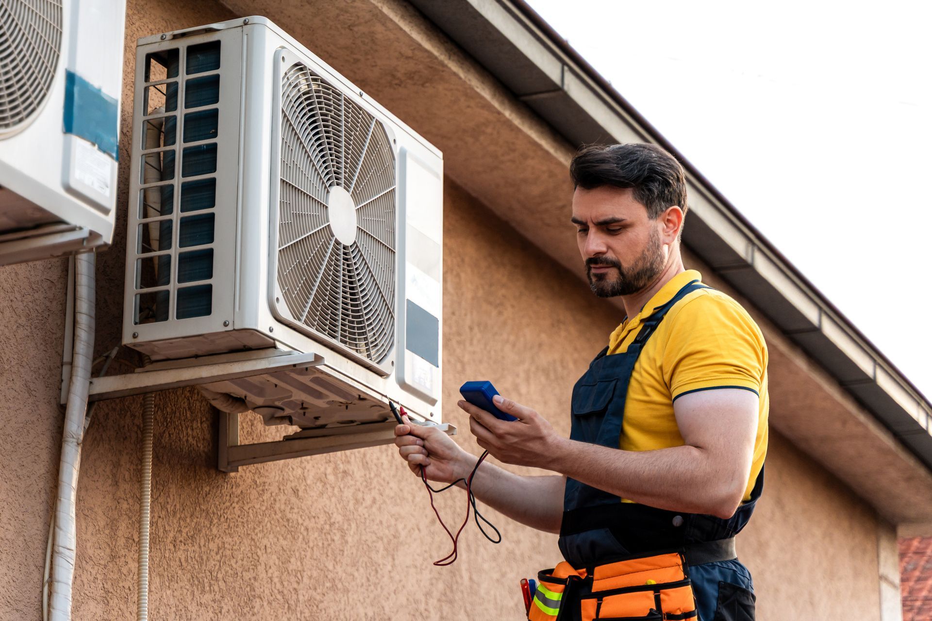 Technician testing outdoor AC unit with diagnostic tool, checking performance and safety