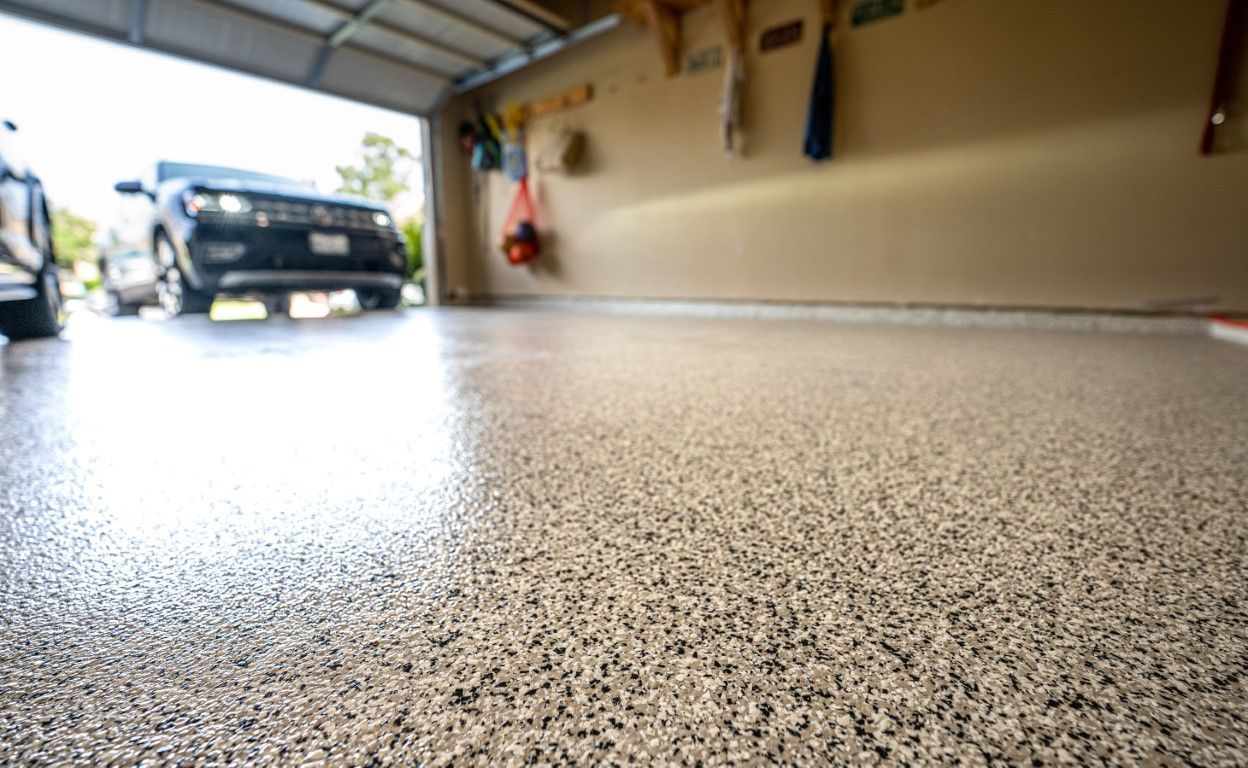 Low-angle view of a garage floor with a car parked near the open door.