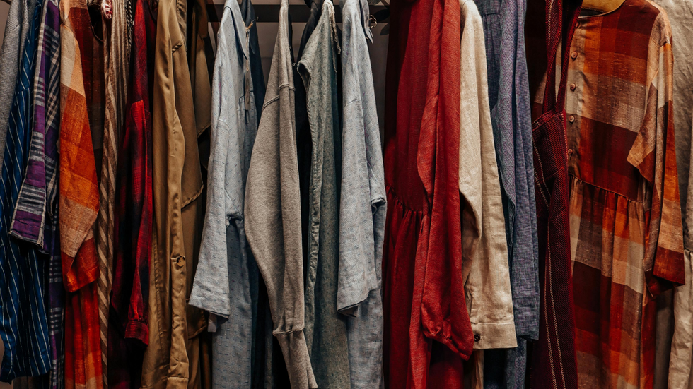A rack filled with various long-sleeved garments in shades of blue, beige, grey, red, and brown plaid.