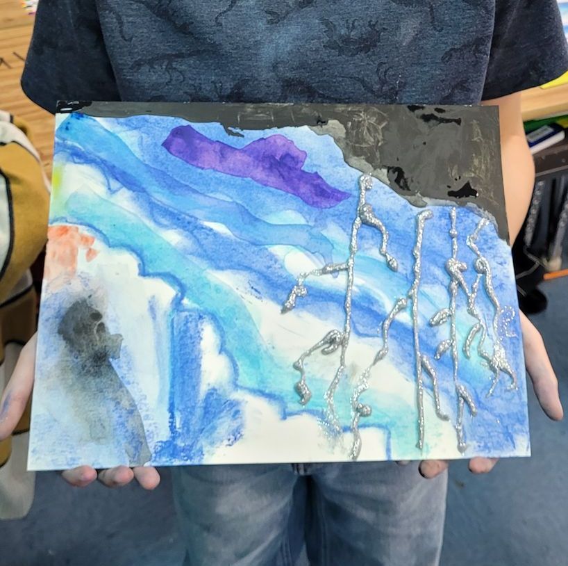 A person is holding a watercolor painting in their hands