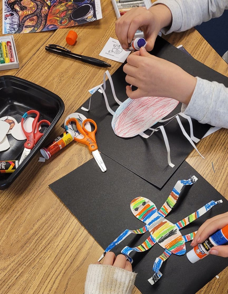 A child is making a spider with glue and scissors