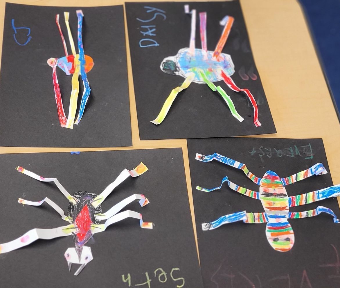 Four children 's drawings of spiders are on a table