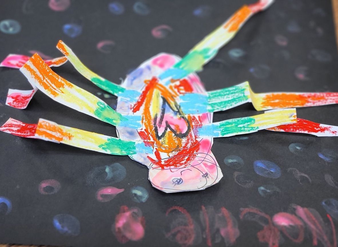 A child 's drawing of a colorful spider on a black background