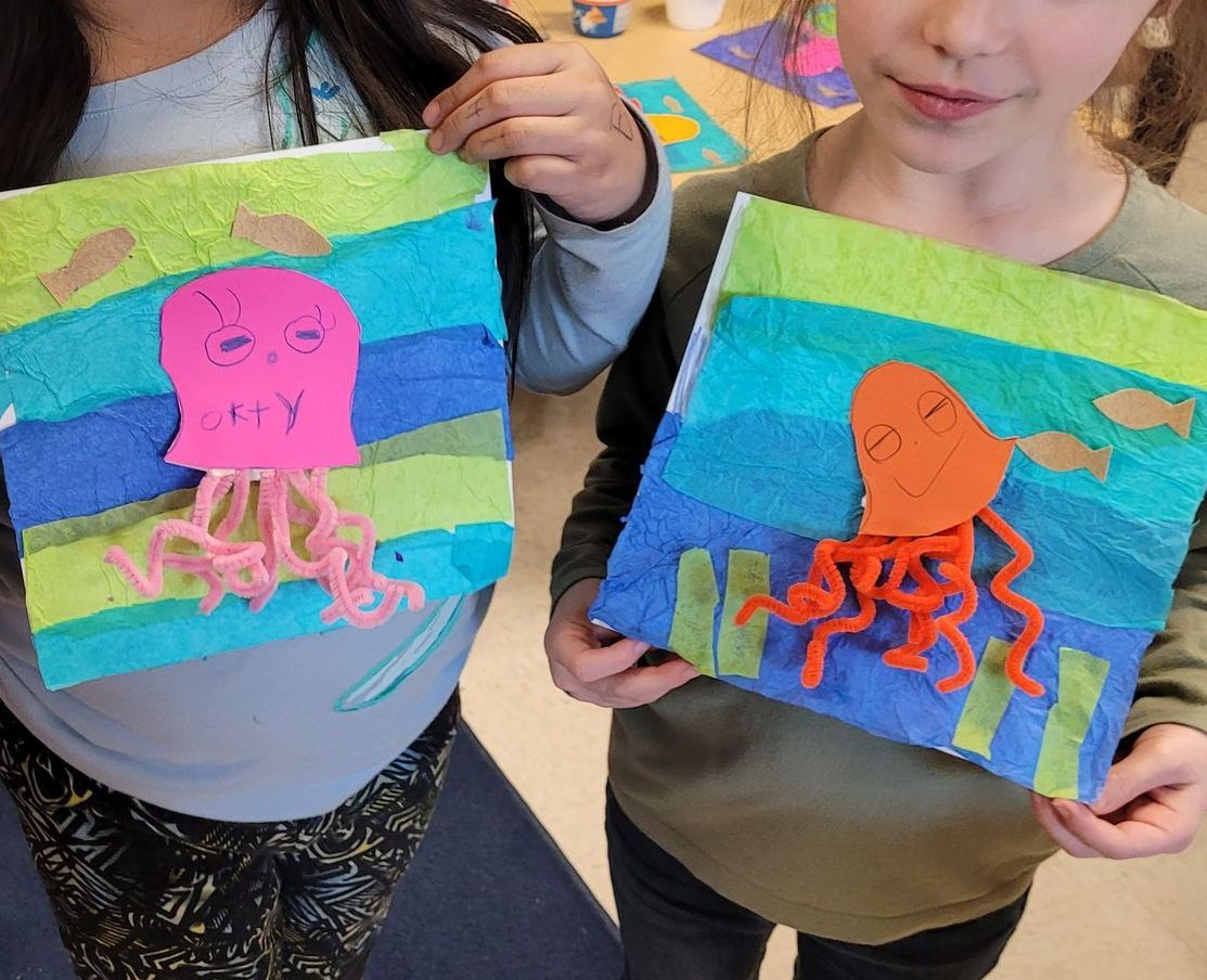 A girl and a boy are holding a painting of an octopus and jellyfish