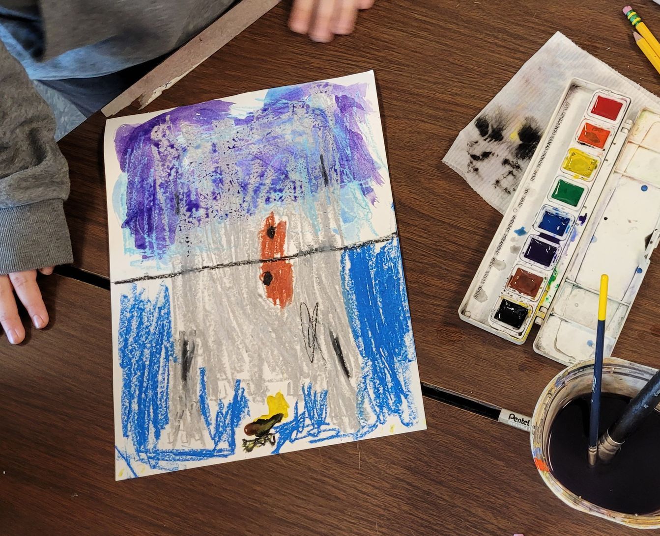 A child is sitting at a table painting with watercolors