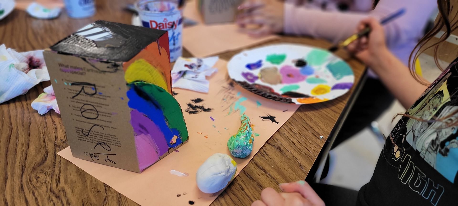 A group of children are sitting at a table painting rocks.