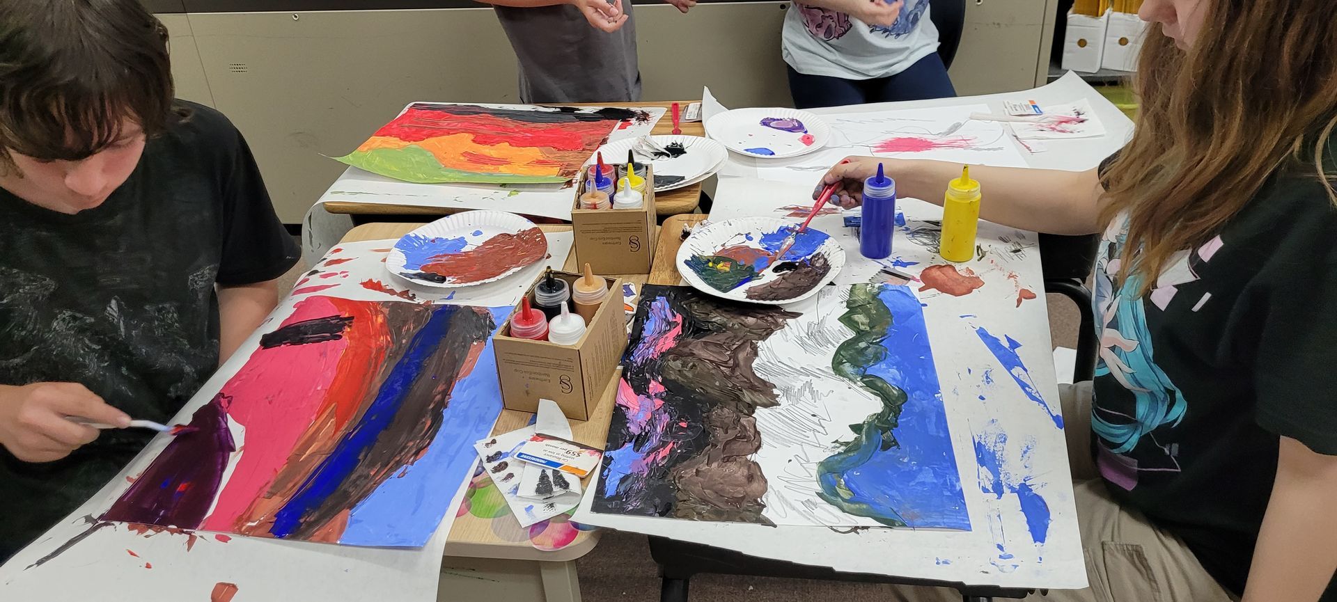 A group of people are sitting at a table painting.