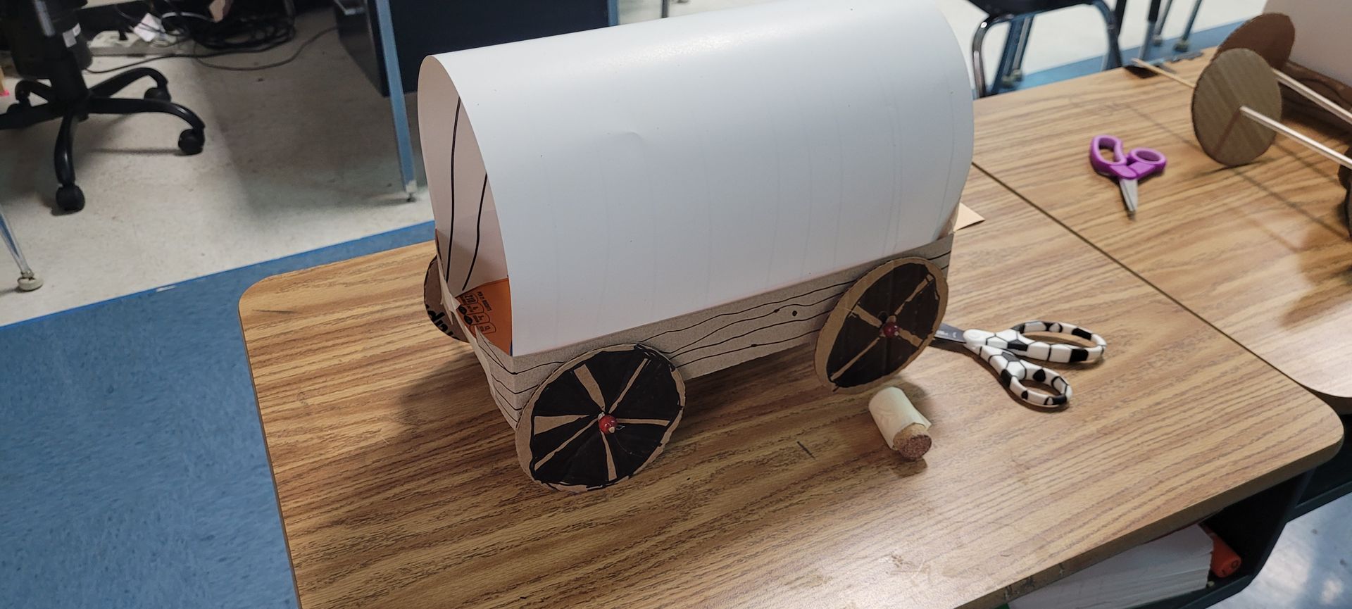 A cardboard wagon is sitting on top of a wooden table.