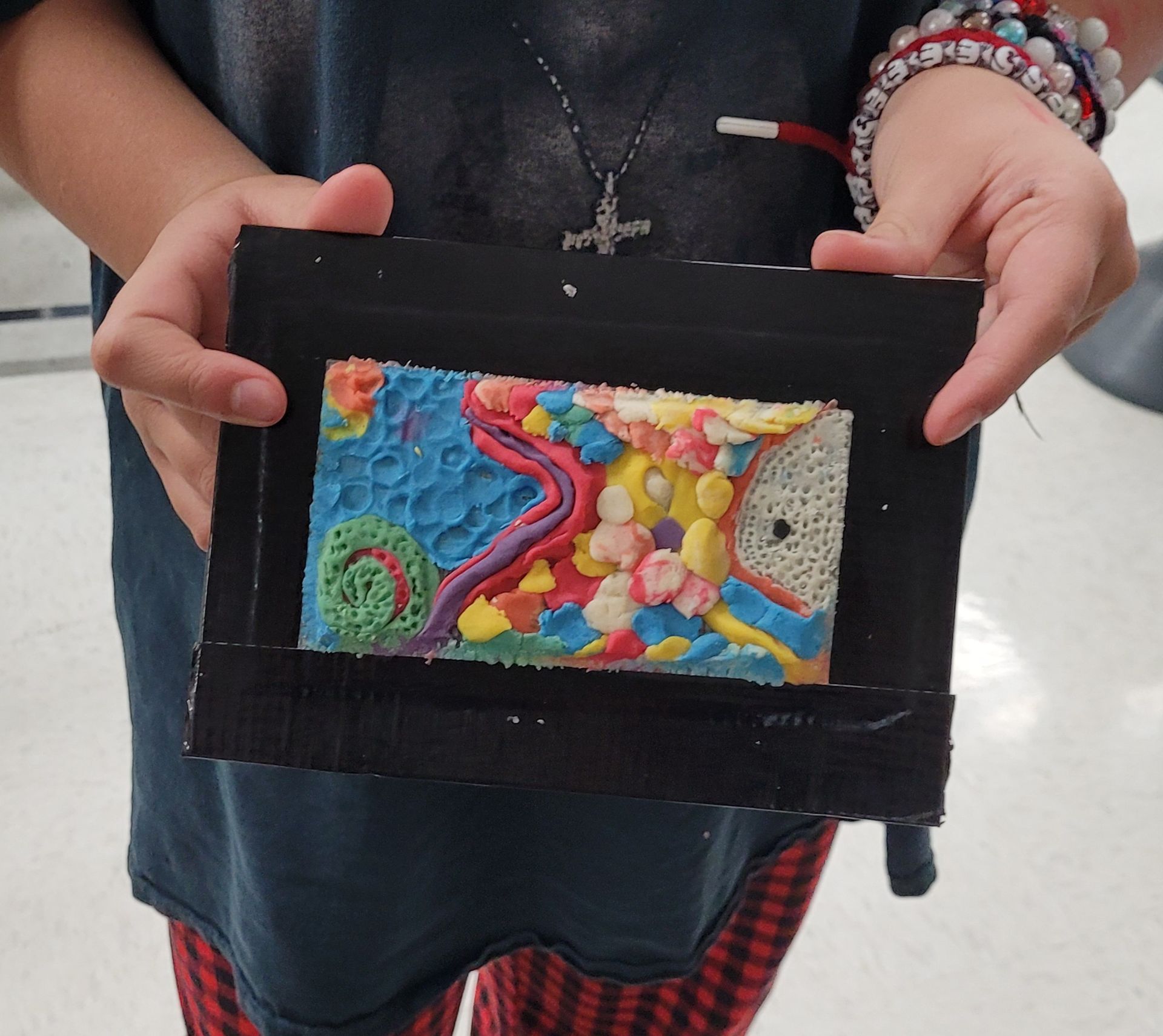 A person is holding a picture frame with a painting on it