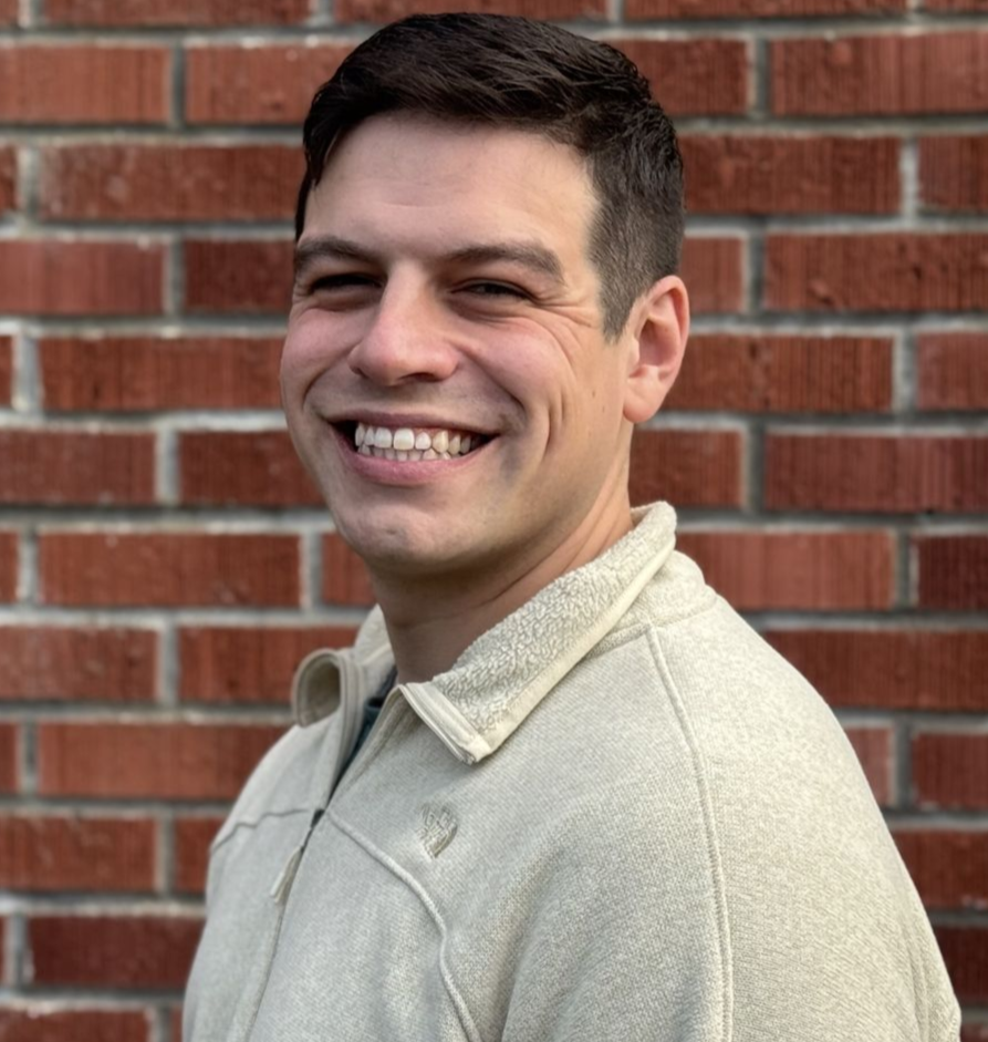 A man with glasses and a beard is smiling for the camera.
