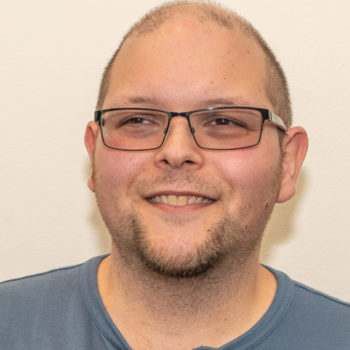 A man with glasses and a beard is smiling for the camera.