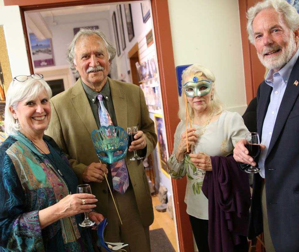 A group of people standing next to each other holding wine glasses and wearing masks.