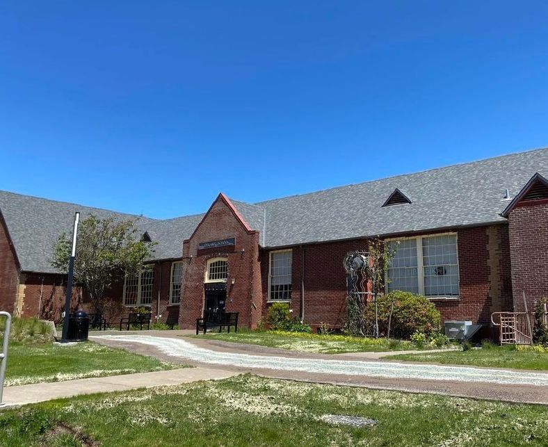 A large brick building with a gray roof and a lot of windows