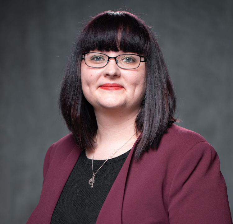 A woman with white hair is sitting at a table smiling.