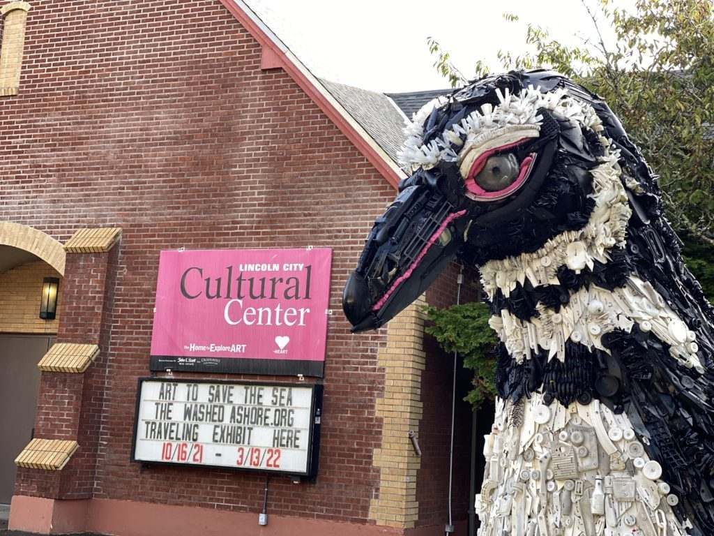 A statue of a bird is in front of a brick building with a sign that says cultural center.